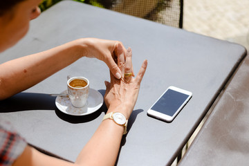 Fototapeta na wymiar Close up on elegant hands in gloves and touch screen mobile smartphone. Woman drinking coffee in restaurant or cafe, summer sunny background.