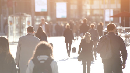 abstract crowd of people walking on the street, unrecognizable silhouettes with back light