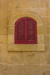 Fototapeta na wymiar Small window with red shutters, Mdina, Valletta, Malta