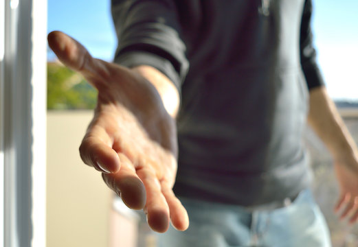 Man raising his hand to the camera to greet. Shake Hands