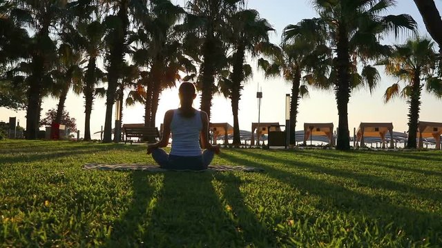 Morning meditation in the park, woman practices yoga on the seashore, Shot on Canon EOS 5D Mark IV in Slow Motion. full HD 1080                     