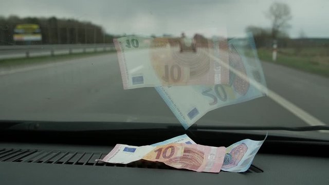 Ten euros placed inside the moving car windshield. Close up.