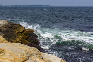 Fototapeta na wymiar Wves crashing against rocky shore in Jamestown Rhode Island