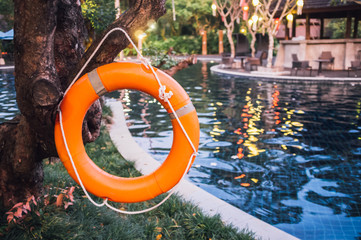 Life buoy or rescue buoy floating near pool to rescue people from drowning man. Safety equipment.