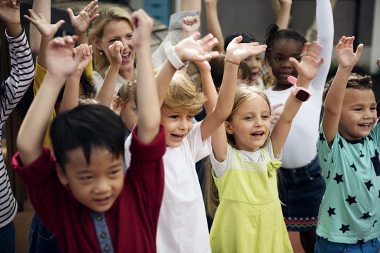 Group of diverse kindergarten students with arms raised