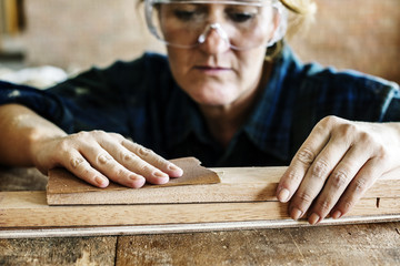 Woman carpenter using sandpaper on a wood