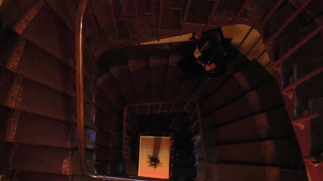 Young woman descending a spiral staircase in an old european building. 4K footage.