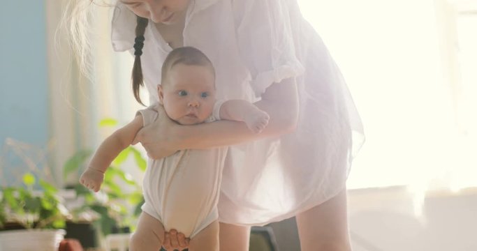 Mother holding baby boy sunny gentle bliss amused interested expression surprised nurse cheeks big eyes watching tender hands moving activity lulling lull dundle rocking child calm charming cute nanny