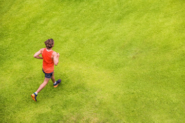 Fototapeta na wymiar Runner man running on summer grass park jogging healthy lifestyle. People working out cardio top view. Copy space on green texture background.
