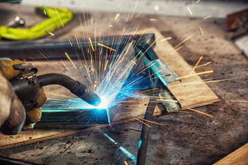 Close-up of a man welds a metal welding machine, sideways flying sparks
