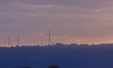 Wind turbines for electricity on a mountain at sunset.