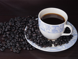 Coffee in cup with coffee beans around.