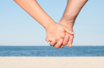 Couple holding hands on the beach.