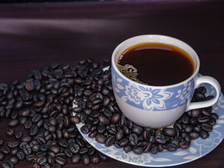 Coffee in cup with coffee beans around.