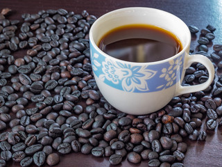 Coffee in cup with coffee beans around.