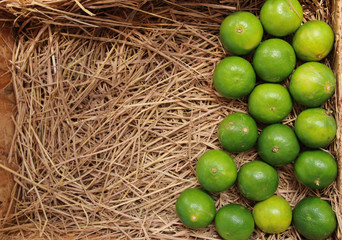 Fresh lime in wood  tray with  straw background. 