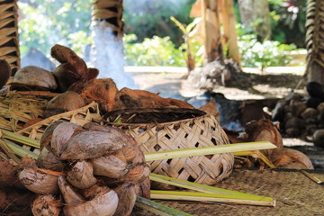 A traditional Samoan cooking area inside a hut with woven baskets and coconuts ready to prepare. - obrazy, fototapety, plakaty