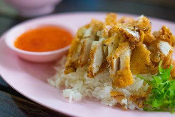 Roasted Chicken Rice with sauce and vegetable on plate on table, shallow focus.