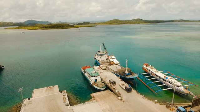 Cargo and passenger port with barges and cargo ships on tropical island. Aerial view:passenger ferry terminal Dapa city .Ferries for transport vehicles and passengers in the port. Philippines, Siargao