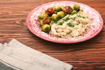 Tasty chicken meat under creamy sauce with brussels sprouts garn
