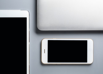 Flat lay and minimalist image of laptop, smartphone and tablet on gray background