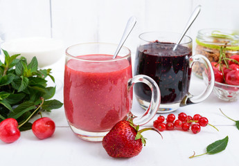 Berry smoothie in of glass cups, yogurt, granola, fresh berries on white wooden background. Proper nutrition. Healthy breakfast. Dietary menu.