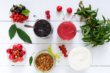 Berry smoothie in of glass cups, yogurt, granola, fresh berries on white wooden table. Top view. Proper nutrition. Healthy breakfast. Dietary menu.