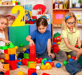Fototapeta na wymiar Children building blocks in kindergarten. Group kids playing toy on floor. Children develop their fingers in a game of cubes number one.