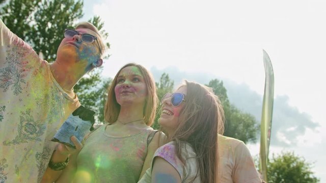 Holi festival of colors. Young people covered with powder taking a selfie. Medium shot