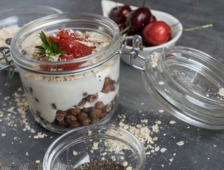 Delicious white yogurt in a glass with chocolate balls, oatmeal and fruit