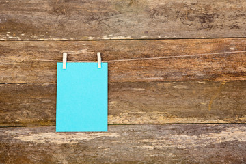 Blue colored paper - cardboard on clothespins hanging againts old timber plank background