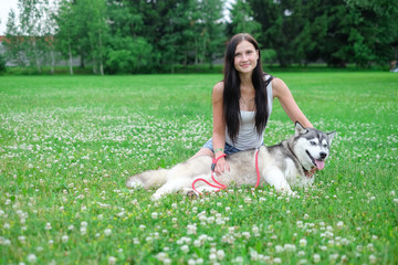 Beautiful young woman playing with funny husky dog outdoors at park