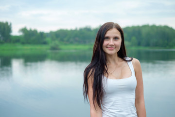 Fototapeta na wymiar Portrait of a beautiful girl in the background of a lake
