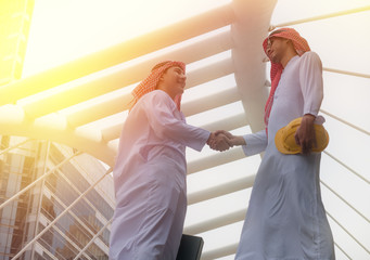 Two arab businessman handshake on city background - 164666154