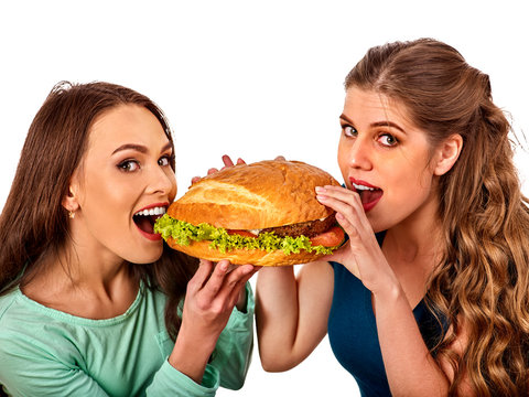 Hamburger fast food with ham and group people. Good Fast food concept. Friends two women eating sandwich junk in party. Girls fool around. Restaurant with giant hamburgers.