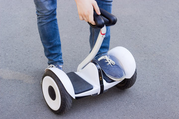 Legs of young man stepping on a self-balancing scooter