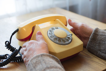 Old female hands hold the phone while waiting for a call.