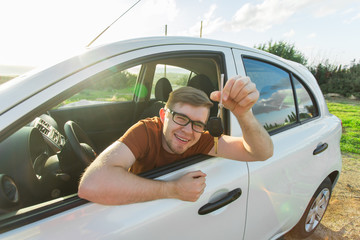 Excited young man showing a car key inside his new vehicle