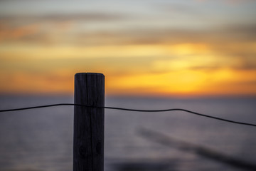 Pfosten an einem Strand im Sonnenuntergang