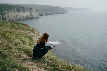 Fototapeta na wymiar Beautiful young woman on a cliff of a mountain near the sea