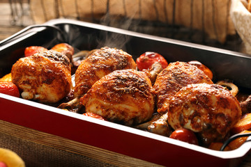 Roasted chicken legs with vegetables on wooden background