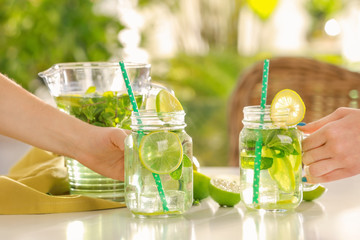 Women taking mason jars of refreshing lemonade on table