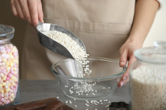 Woman pouring crispy rice balls into glass bowl on table
