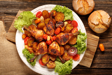 Roasted chicken legs with baked potato on the plate