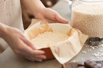 Woman holding baking dish with rice dessert on table