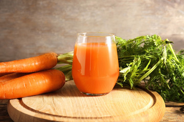 Glass of fresh carrot juice on wooden board