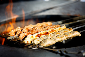 Eastern dish of meat kebab cooked on the skewer over the fire in the street