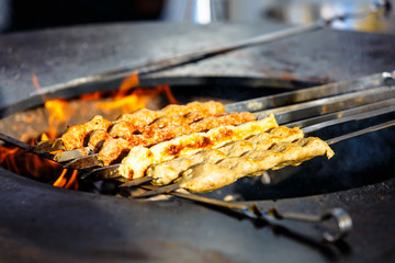 Eastern dish of meat kebab cooked on the skewer over the fire in the street