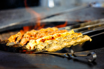 Eastern dish of meat kebab cooked on the skewer over the fire in the street
