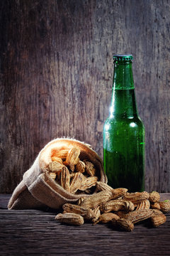 Boiled Peanuts and beer on wood background